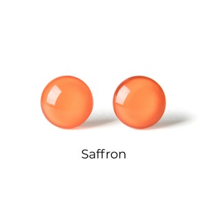 Op de afbeelding: Een paar ronde oranje oorbelletjes. De oorbelletjes zijn gemaakt van glas en hebben een gladde, glanzende afwerking. De oorbelletjes worden "Saffraan" genoemd.