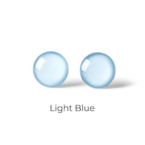 Peut inclure: Une paire de boucles d'oreilles en verre bleu clair. Les boucles d'oreilles sont rondes et ont une finition lisse et brillante.