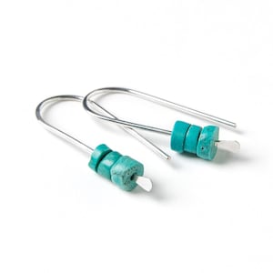 May include: A pair of silver hoop earrings with turquoise stone accents. The earrings are simple and elegant, perfect for everyday wear.