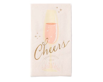 May include: White paper napkins with a gold design of a champagne flute and the word "Cheers" with the text "Bachelorette Bash" underneath.