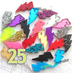 May include: A collection of 25 acrylic lightning bolt charms in various colors, including glitter, mirror, and solid colors. The charms have a hole at the top for attaching to jewelry or other crafts.