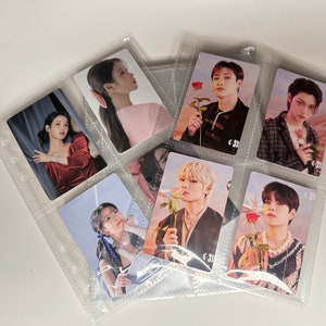 May include: Clear plastic trading card binder filled with K-pop star photo cards. The cards feature various performers holding roses. The binder is open, displaying multiple cards in individual pockets. The background is a plain white surface.