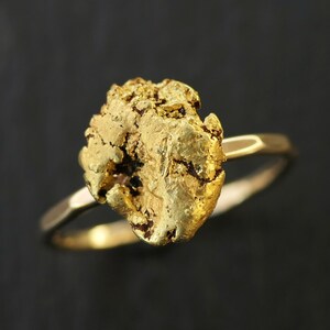 Puede incluir: Un anillo de oro con una gran pepita de oro irregular como pieza central.