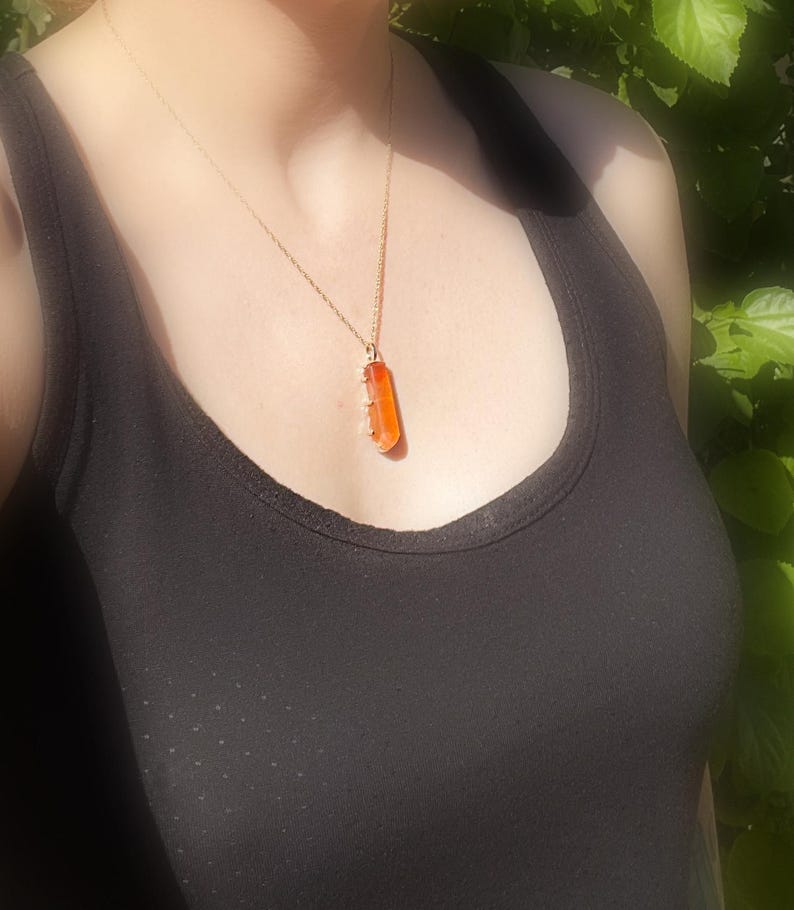 May include: A gold chain necklace with a long, rectangular orange pendant.