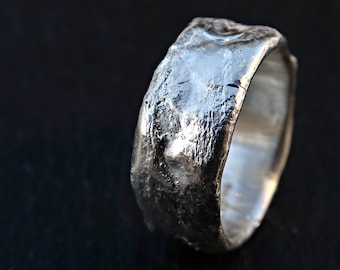 以下が含まれることがあります： テクスチャ加工が施され、ハンマーで叩かれた仕上げのシルバーリング。リングは幅広で、丸みを帯びたバンドです。