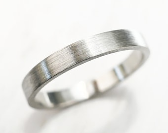May include: A simple silver band ring with a brushed finish.