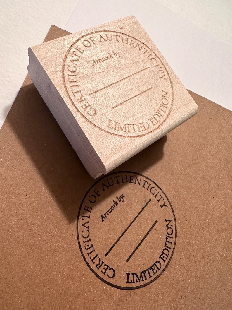 May include: A wooden stamp with a round design that says "Certificate of Authenticity Limited Edition" and has a blank space for "Artwork by:".