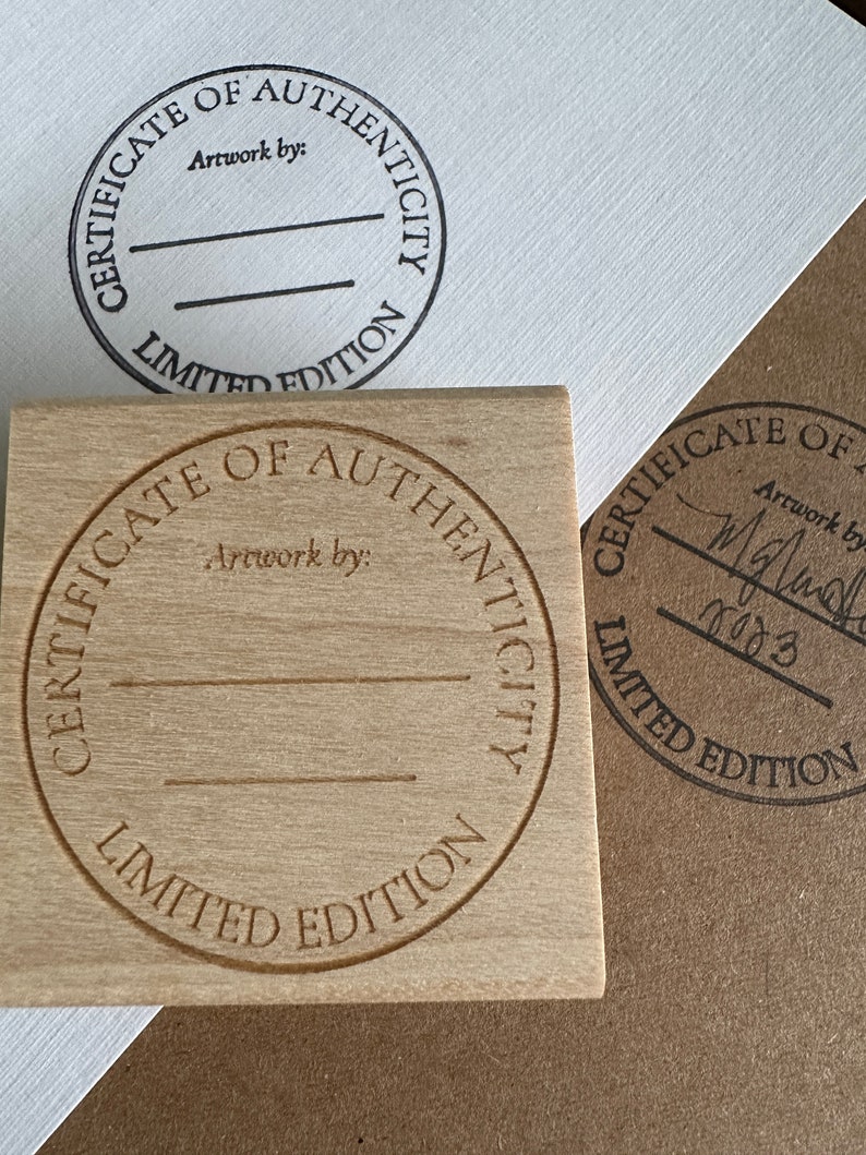 May include: A wooden stamp with a circular design that reads "Certificate of Authenticity Limited Edition". The stamp is blank and ready to be used.