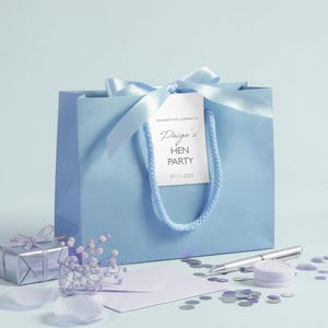 Personalised hen party gift bags with custom tags and ribbons, perfect for adding a special touch to hen do favours. Made from 100% recycled paper with reinforced bases and soft rope handles, these elegant bags can be customised with names, dates, or messages. Ideal for presenting gifts or party favours in style.
