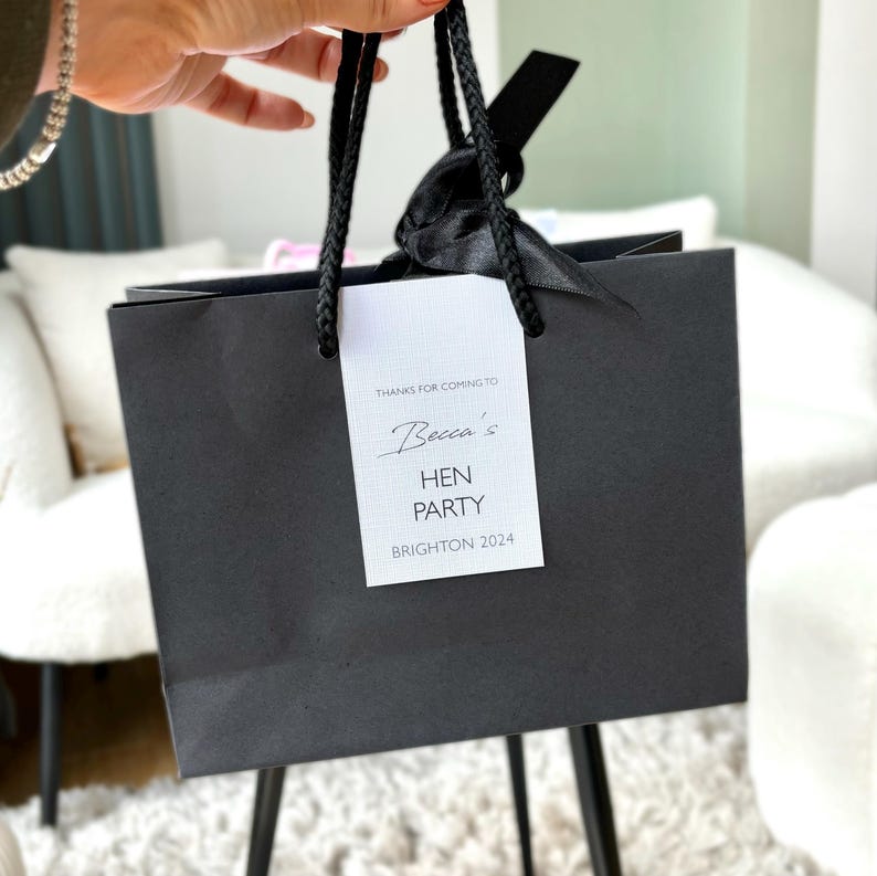 Personalised hen party gift bags with custom tags and ribbons, perfect for adding a special touch to hen do favours. Made from 100% recycled paper with reinforced bases and soft rope handles, these elegant bags can be customised with names, dates, or messages. Ideal for presenting gifts or party favours in style.