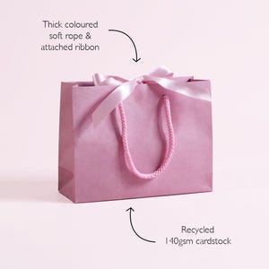 Personalised hen party gift bags with custom tags and ribbons, perfect for adding a special touch to hen do favours. Made from 100% recycled paper with reinforced bases and soft rope handles, these elegant bags can be customised with names, dates, or messages. Ideal for presenting gifts or party favours in style.
