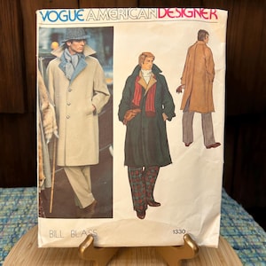 May include: Vintage Vogue American Designer sewing pattern by Bill Blass. The pattern features illustrations of men's coats and outerwear. The cover has the text "VOGUE AMERICAN DESIGNER" and "BILL BLASS" printed on it. The pattern number is 1330.