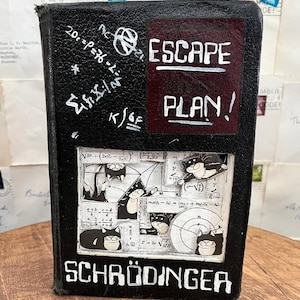 May include: Black book with the words "ESCAPE PLAN!" and "SCHRÖDINGER" in white lettering. The book has a collage of images and mathematical equations, including cartoon cats. The background is a collection of old letters.