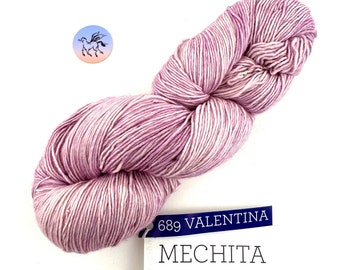 Puede incluir: Un ovillo de hilo de color lila claro etiquetado como "689 VALENTINA MECHITA" con los detalles: "FINGERING - 420 yd (384 m) - 100 g, 26-30 sts = 4 inches -  Needle Size: US 2-4 OR 2.75-3.5 mm, 100% Superwash Merino Wool."