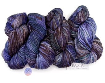 May include: Close-up of several skeins of thick, hand-dyed yarn in shades of purple, blue, and brown. The yarn is chunky and textured, with a soft, inviting appearance. A small tag with text is visible. Ideal for knitting and crochet projects.