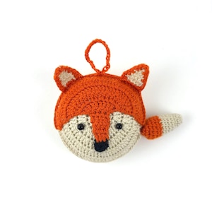 Circular tape measure covered by a hand crocheted fox face in orange and ivory. Black eyes and a nose all created by detailed crochet. Even the tail half orange and ivory is on the side and is the pull to the tape. The shaped ears sit atop the tape.