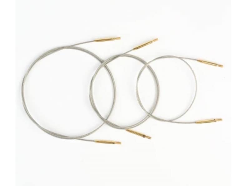 Pu&ograve; includere: Tre ferri circolari con cavi argentati e punte color oro sono disposti su sfondo bianco. I ferri sono di diverse dimensioni, con i cavi che formano anelli. Le punte sembrano essere in metallo.