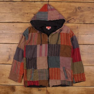 May include: A patchwork hoodie jacket with a full zip and hood. The jacket features a variety of colours and patterns, including squares and stripes in shades of red, brown, and green. The jacket has two front pockets and a black lining.