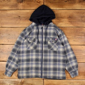 Peut inclure: Un sweat à capuche zippé à manches longues avec un motif à carreaux dans des tons bleu marine, gris et crème. Le vêtement comprend une capuche bleu marine unie avec cordons de serrage, une fermeture éclair frontale et deux poches poitrine.