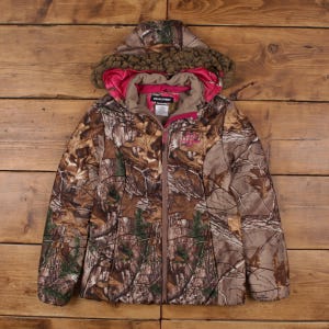 May include: A camouflage jacket with a hood lined with pink fabric and faux fur trim. The jacket features a zip-up front. The jacket is designed with a woodland camouflage pattern. The word "Realtree" is visible on the tag.