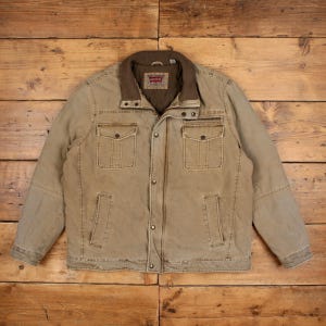 May include: A tan utility jacket featuring a brown corduroy collar, a front zip closure with metal snap buttons, two chest pockets with flaps, and two lower hand pockets. The interior label displays the Levi's brand name and logo.