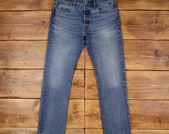 Calça jeans Levi's 501, tamanho 34x34, azul, corte reto regular, desbotada, com fechamento por botões e etiqueta vermelha.