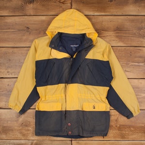 May include: A yellow and navy blue striped hooded jacket with a zip closure and a drawstring waist. The jacket has two front pockets and a logo on the right pocket. The jacket is made by Nautica.