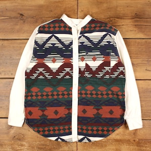 May include: A long-sleeved shirt with a white body and sleeves. The front features a colorful geometric pattern in shades of red, green, navy, and white. The shirt has a button-down front and a single chest pocket.