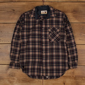 May include: A long-sleeved plaid shirt in shades of brown, navy, and red. The shirt features a button-down front, a chest pocket, and a dark blue collar. The shirt has the "LOBO" brand label.