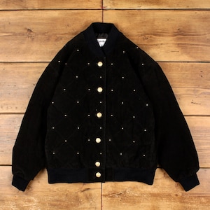 May include: A black quilted bomber jacket featuring a diamond pattern with small gold studs at each intersection. The jacket has a ribbed collar, cuffs, and hem, with a front button closure using gold-toned buttons and a label at the inner neck.