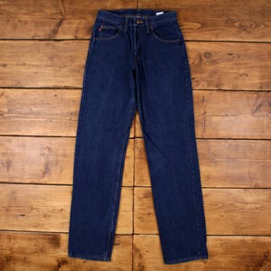 Op de afbeelding: Donkerblauwe denim jeans met een klassiek vijf-zakken ontwerp. De jeans hebben een rechte pijp en een knoop- en ritssluiting. De denim is een effen, donkere wassing, op een houten ondergrond.