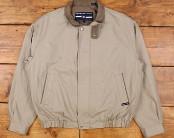 May include: Tan Members Only Mariner jacket with a brown collar and a button closure. The jacket has two front pockets and a small logo on the left side. The jacket is made of a lightweight material and has a ribbed hem and cuffs.