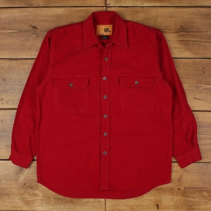 May include: A solid red long-sleeve button-down shirt featuring a pointed collar, two chest pockets with buttoned flaps, and a central button placket. The interior neck label displays the text OR in a black font on a tan rectangular background.