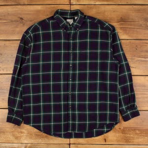 Puede incluir: Camisa de manga larga con estampado de cuadros en azul marino, verde y blanco. La camisa tiene cuello abotonado y un bolsillo en el pecho. El logo de Gap es visible en el cuello. La camisa está abotonada.