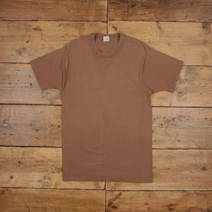 Könnte beinhalten: Ein braunes T-Shirt mit kurzen Ärmeln auf einem Holzgrund.