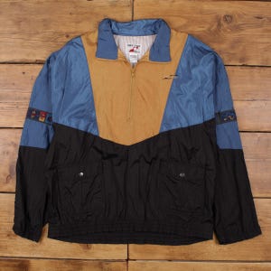 May include: A vintage color-blocked jacket with a half-zip closure. The jacket features a color scheme of blue, tan, and black. It has two front pockets and elastic cuffs. The jacket has a small logo on the chest and the brand name "Tuff Stuff" on the collar.