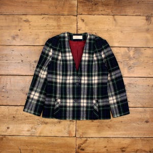 Peut inclure: Un blazer à carreaux avec un col en V et une fermeture à un seul bouton. Le blazer est vert, blanc et noir avec une doublure rouge.