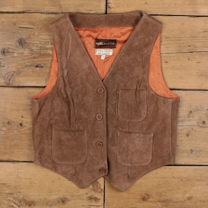 Puede incluir: Chaleco de ante marrón con cuello en V, tres botones y dos bolsillos delanteros. El chaleco tiene un forro naranja y una etiqueta que dice "Split End Ltd."