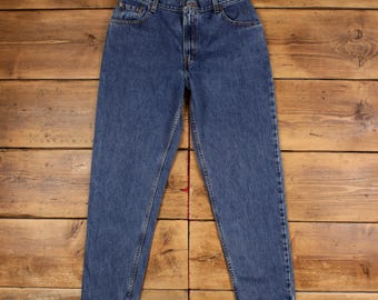 May include: Blue denim jeans with a classic five-pocket design. The jeans have a straight leg cut and a button and zipper closure. The denim has a medium wash and a red tag is visible on the back.