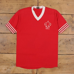 Könnte beinhalten: Rotes Vintage-T-Shirt mit weißem V-Ausschnitt und Ärmelbündchen. Die Ärmel haben weiße Streifen. Ein weißes Fleur-de-Lis-Emblem und die Buchstaben "B.S.A." sind auf der Vorderseite aufgedruckt. Das Shirt ist aus weichem, bequemem Material.