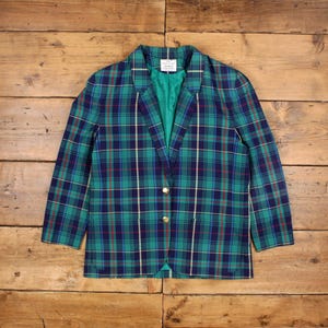 Puede incluir: Una chaqueta de cuadros verde, azul, rojo y blanco con botones dorados.