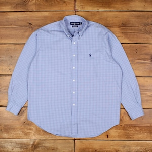 Könnte beinhalten: Ein hellblaues Button-Down-Hemd mit Karomuster. Das langärmlige Hemd hat einen Button-Down-Kragen und ein kleines gesticktes Logo auf der Brust. Das Hemd ist aus leichtem Stoff gefertigt.