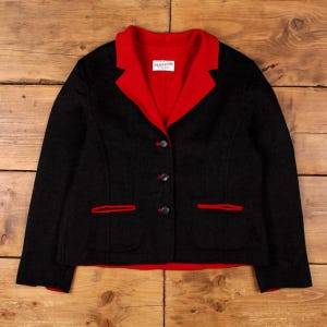 May include: A black jacket with a red collar and red pocket trim. The jacket features three buttons and a small white label with the brand name "Pendleton" on the collar. The jacket is a classic style.
