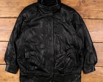 May include: Black leather jacket with a high collar and button closure. The jacket has two front pockets and a ribbed hem. The sleeves are long and have ribbed cuffs. The jacket is made of a soft, supple leather.