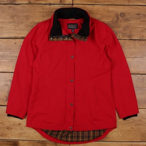 Könnte beinhalten: Rote Jacke mit schwarzem Kragen und Manschetten. Die Jacke hat eine Knopfleiste vorne und zwei Taschen. Das Innenfutter und die Kragendetails weisen ein Karomuster auf. Die Jacke ist von Pendleton.