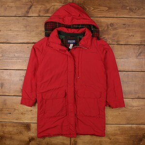 Puede incluir: Chaqueta con capucha Lands' End de color rojo brillante con capucha y cuello forrados con cuadros. La chaqueta tiene dos bolsillos delanteros y cierre de cremallera. La chaqueta está sobre una superficie de madera.