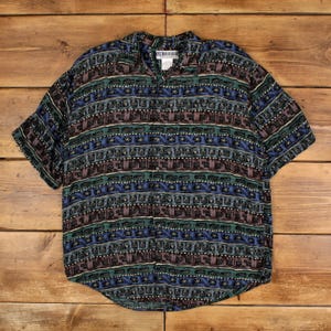 以下が含まれることがあります： 青、緑、茶色、白の色合いの幾何学模様の半袖ボタンダウンシャツ。 シャツは襟付きでゆったりとしたフィット感です。 シャツは軽量の生地で作られています。