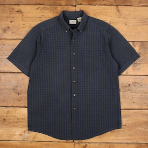 May include: A short-sleeve button-down shirt in a dark navy blue and olive green plaid pattern. The shirt features a pointed collar, a single chest pocket on the left side, and a front button placket with dark buttons. An L.L.Bean label is visible.