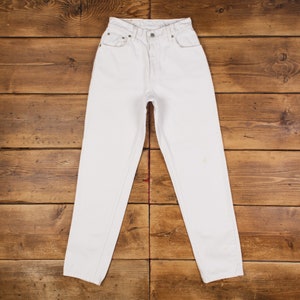 May include: White denim jeans with a straight leg fit. The jeans have a classic five-pocket style and a button fly.