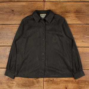 Peut inclure: Une chemise boutonnée gris foncé à manches longues. La chemise a un col et des boutons sur le devant. L'étiquette Pendleton est visible en haut. La chemise est posée à plat sur une surface en bois.